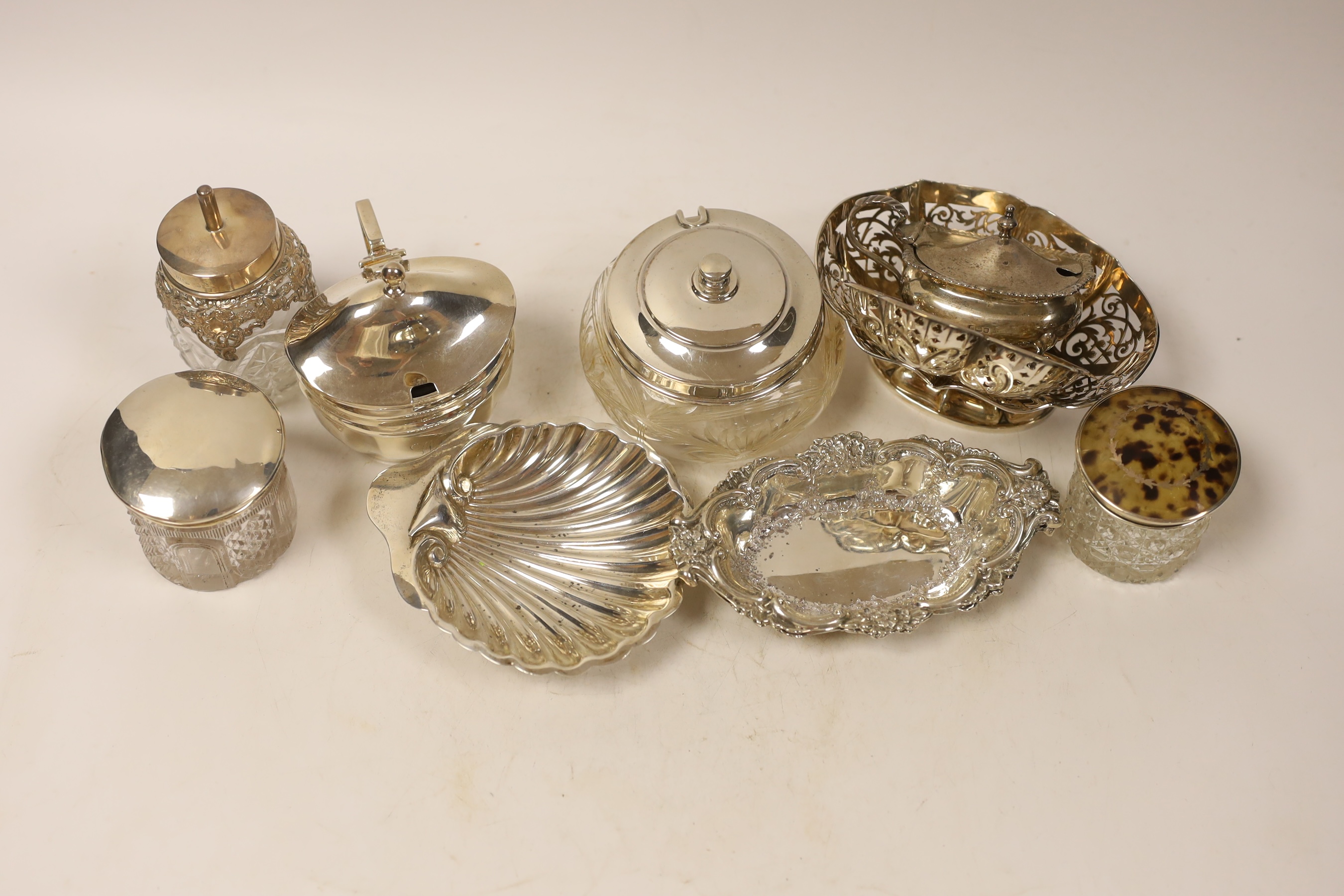 A group of silverware including a pair of bonbon dishes, butter shell, pierced dishes, toilet jars and a George III mustard, London, 1806, etc.